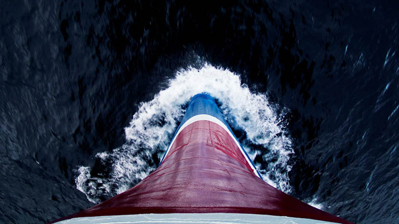 Auf Kurs punkto Nachhaltigkeit: Die Fotografie zeigt den Kiel eines Schiffes, das den dunklen Ozean durchpflügt. Steil von oben fotografiert.